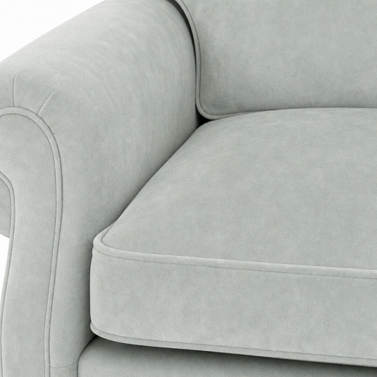Close-up of a light gray upholstered sofa showing the armrest, back cushion, and seat cushion with clean tufted piping.