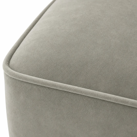 Close-up of a light gray upholstered furniture corner with a soft velvet-like texture and a piped edge, shown against a white background.