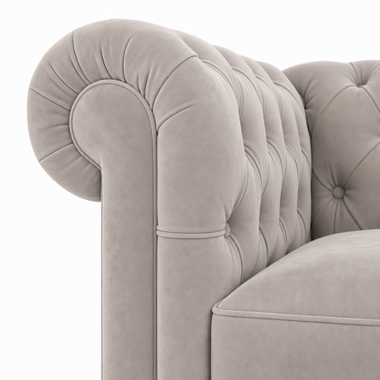 Close-up of a classic Chesterfield armchair upholstered in light beige velvet, showing the tufted backrest and rolled armrest against a plain white background.
