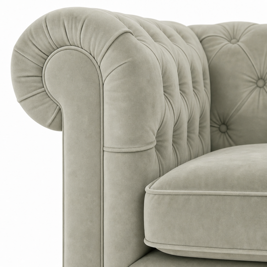 Close-up of a classic Chesterfield armchair upholstered in light sage green velvet, showing the tufted backrest and rolled armrest against a white background.