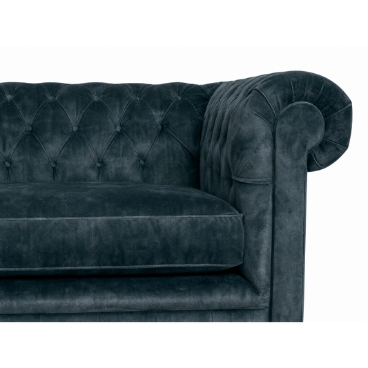 Dark blue velvet sofa with tufted backrest on a white background
