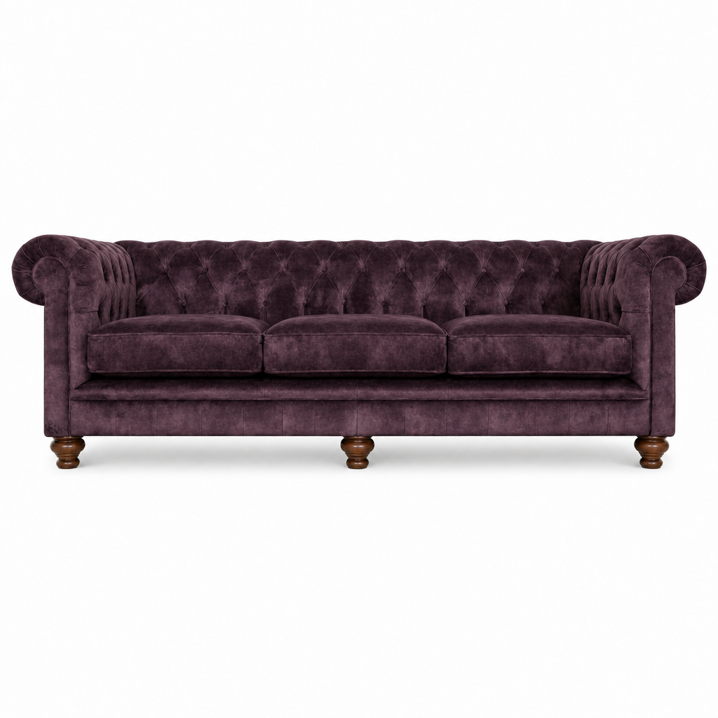A classic Chesterfield-style sofa upholstered in deep plum purple velvet, featuring tufted button detailing, rolled arms, three seat cushions, and turned wooden legs, shown against a plain white background.