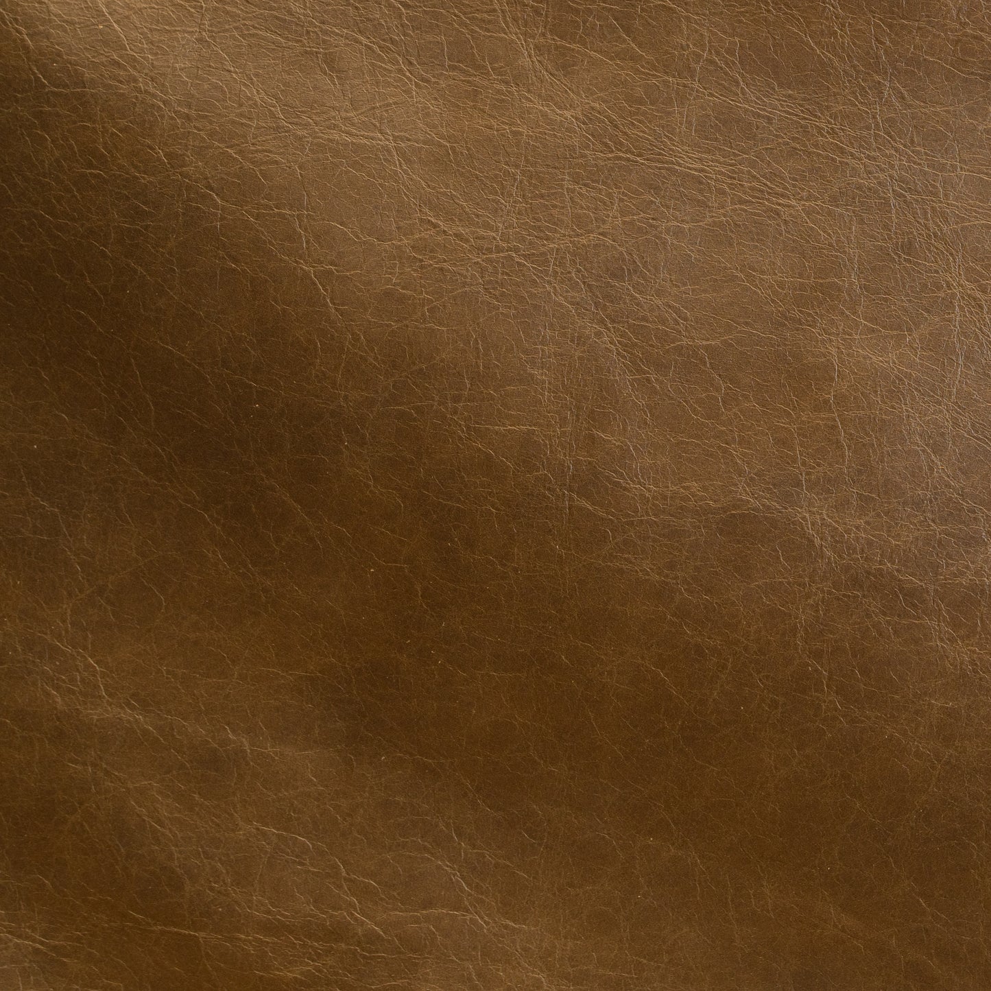 A close-up of brown leather texture with visible grain and subtle tonal variation.