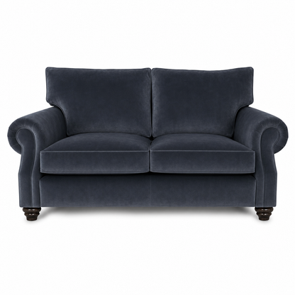 A classic two-seater loveseat sofa upholstered in dark navy blue velvet fabric, featuring rolled arms, two back cushions, and dark wooden turned legs, shown against a plain white background.