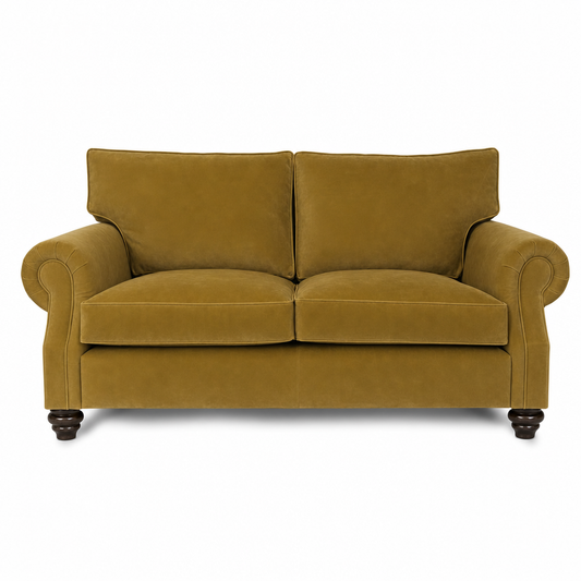 A classic two-seater loveseat sofa upholstered in a textured mustard yellow velvet fabric, featuring rolled arms, dark wooden turned legs, and a clean white background.