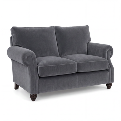 A dark gray velvet loveseat with rolled arms, two back cushions, two seat cushions, and dark wooden turned legs, shown on a plain white background.
