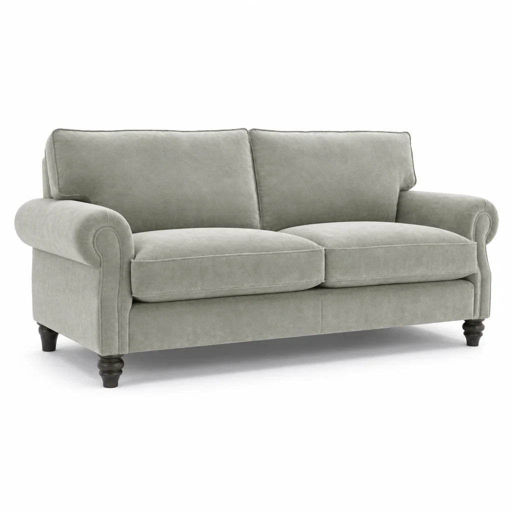 A light sage green upholstered loveseat with rolled arms, two back cushions, two seat cushions, and dark turned wooden legs, shown on a plain white background.