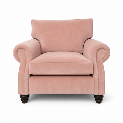 A classic pink velvet armchair with rolled arms, a high backrest, and dark wooden turned legs, shown against a plain white background.