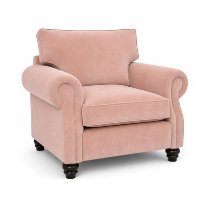 A classic pink velvet armchair with rolled arms, a high back cushion, and dark turned wooden legs, shown on a plain white background.