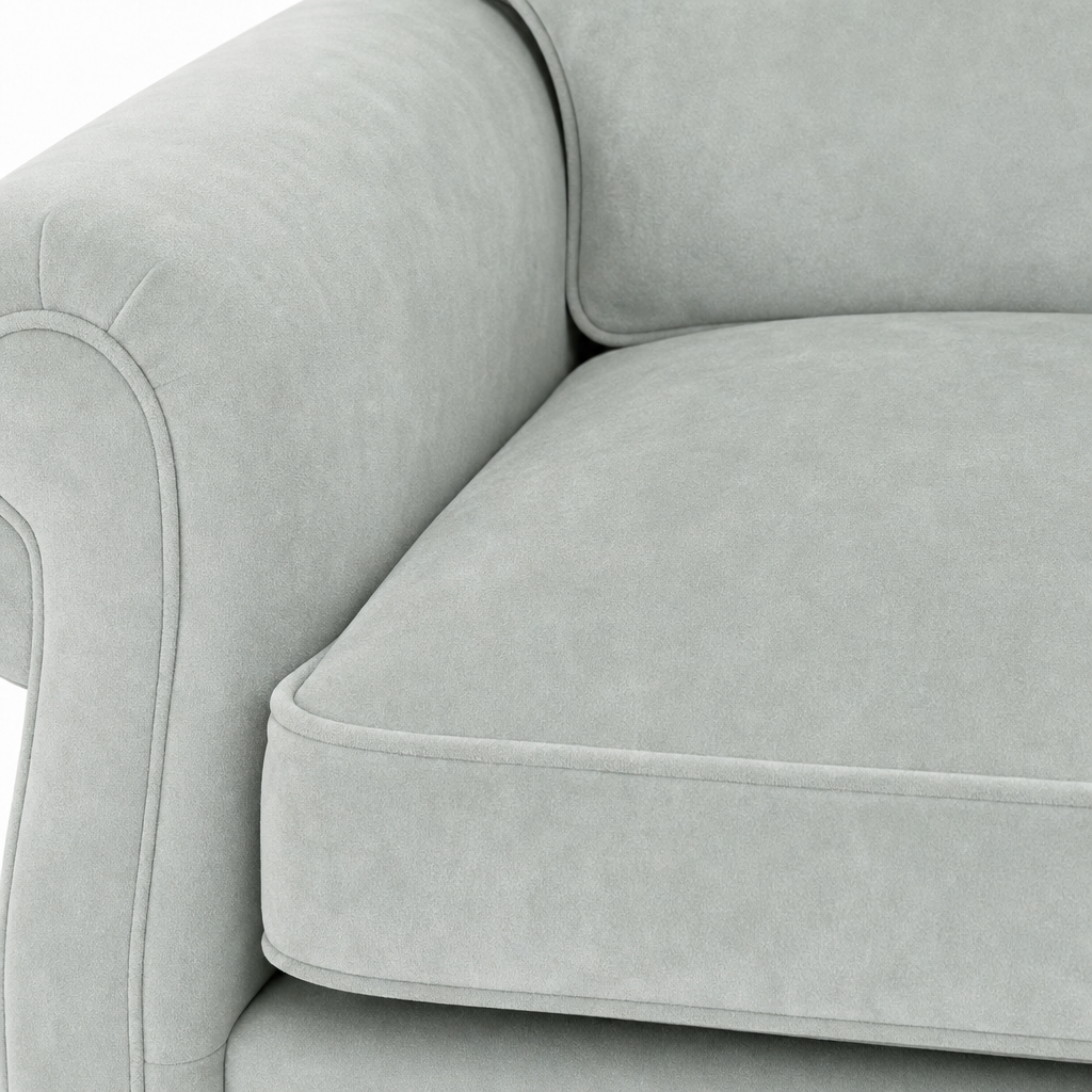Close-up of a light gray upholstered sofa showing the armrest, back cushion, and seat cushion with clean tufted piping.