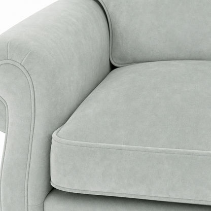 Close-up of a light gray upholstered sofa showing the armrest, back cushion, and seat cushion with clean tufted piping.
