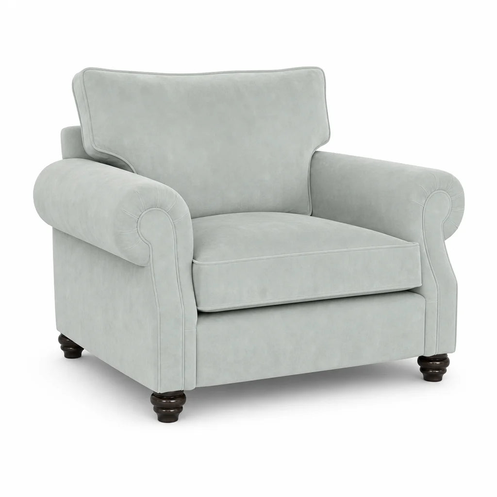 A light sage green upholstered armchair with rolled arms, a high back cushion, and dark wooden turned legs, shown on a plain white background.