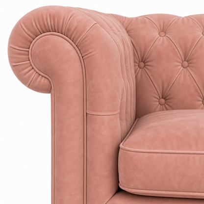 Close-up of a dusty pink velvet Chesterfield armchair showing the tufted backrest, rolled armrest, and cushion against a plain white background.