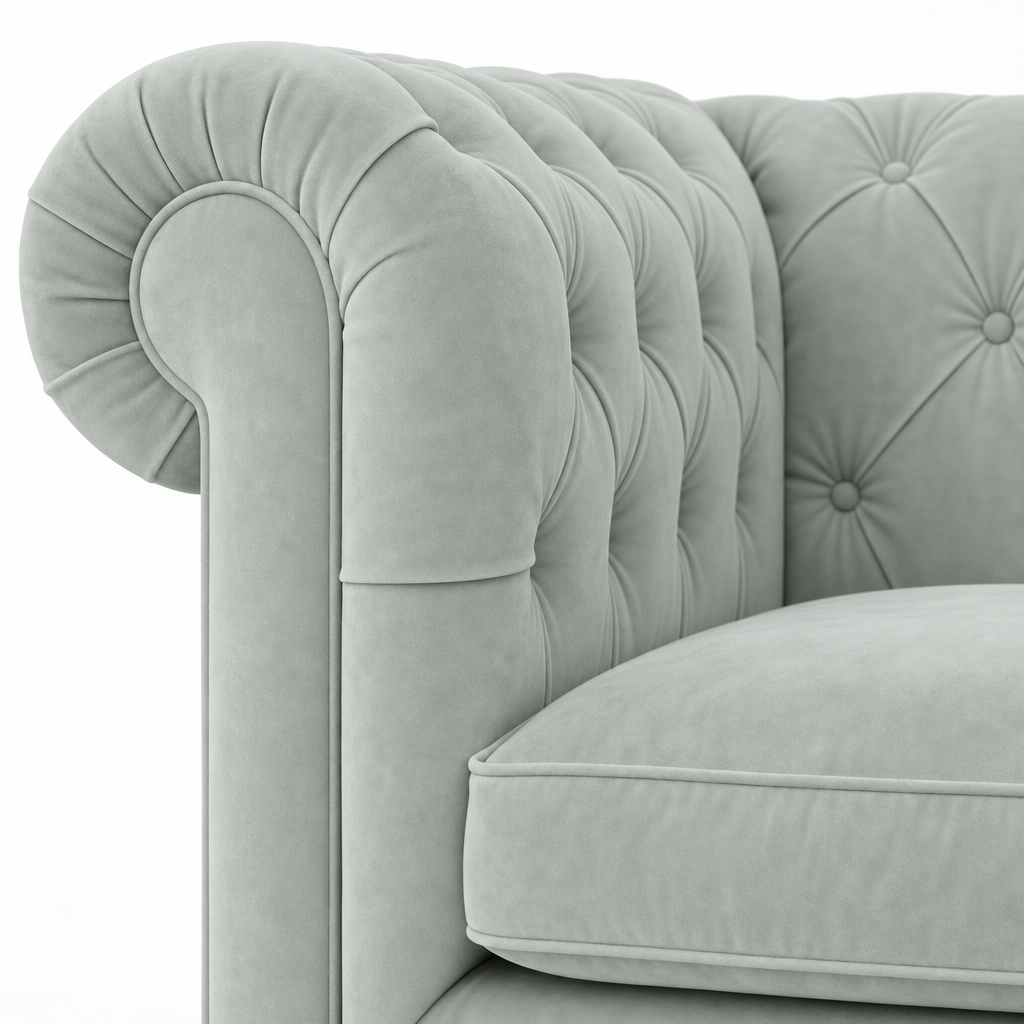 Close-up of a light blue tufted velvet armchair showing the rolled arm, button tufting, and cushion.