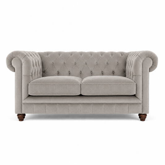 A classic Chesterfield loveseat sofa upholstered in light gray fabric, featuring a tufted diamond pattern on the backrest and seat, rolled arms, two loose seat cushions, and dark wooden legs, shown against a plain white background.