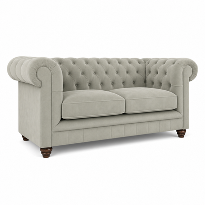 A classic Chesterfield loveseat sofa upholstered in a light gray-beige textured fabric, featuring deep button tufting on the backrest and seat, rolled arms, two loose seat cushions, and dark brown turned wooden legs, shown on a plain white background.