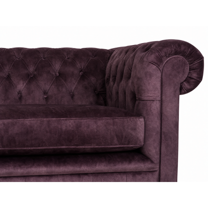 Purple velvet sofa with tufted backrest on a white background