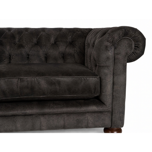 Dark gray tufted sofa with wooden legs on a white background