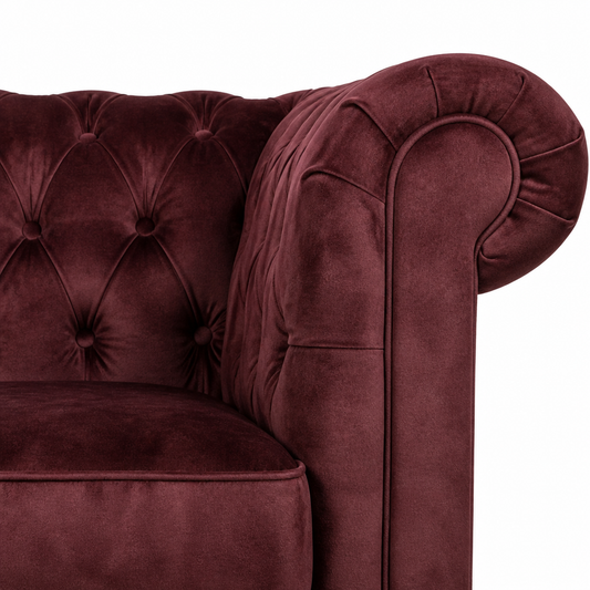 Close-up of a burgundy velvet armchair with tufted backrest on a white background