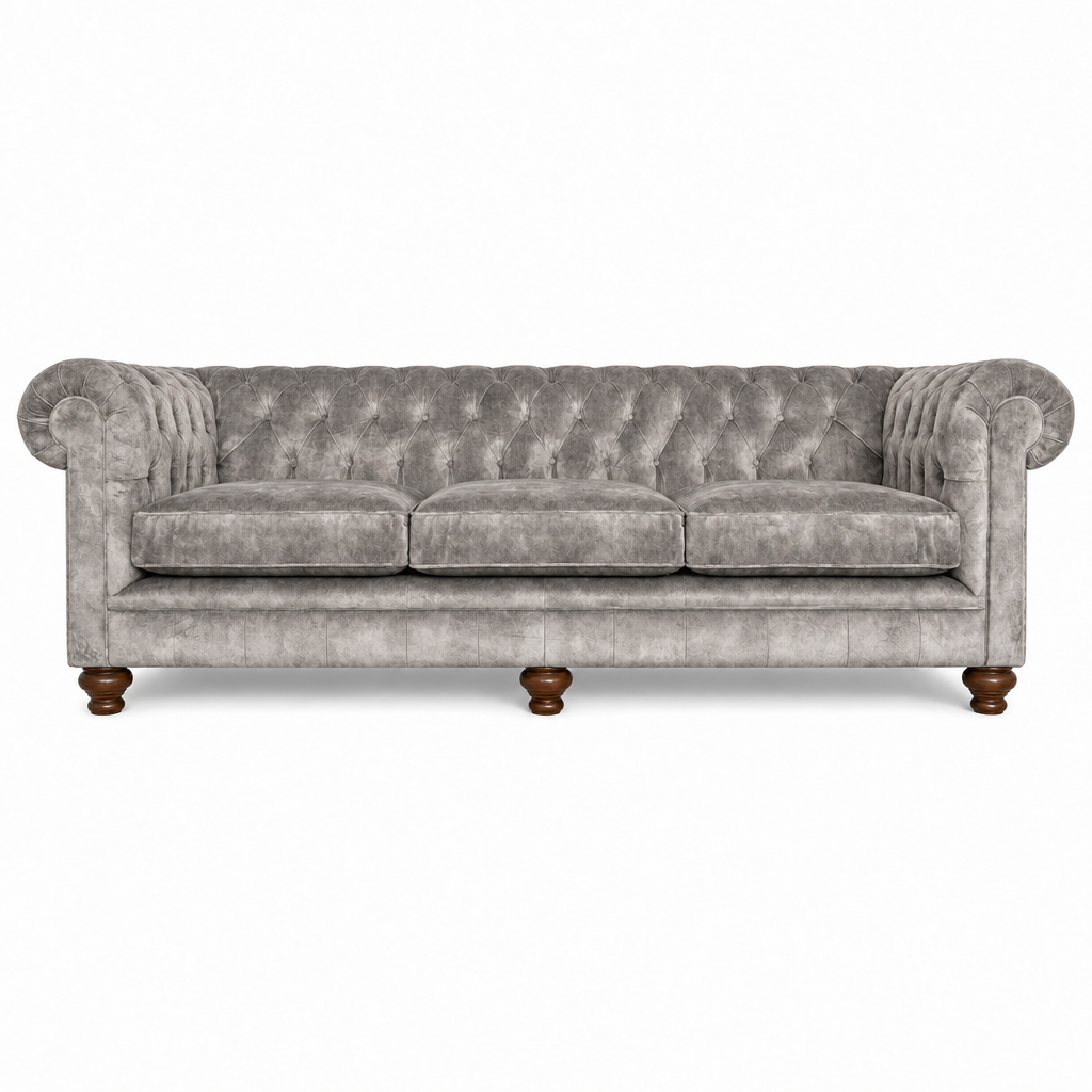 A classic Chesterfield-style three-seater sofa upholstered in textured gray velvet, featuring deep button tufting, rolled arms, and dark brown turned wooden legs, shown against a plain white background.