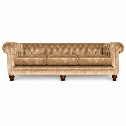 A classic Chesterfield three-seater sofa upholstered in beige velvet, featuring deep button tufting, rolled arms, and dark brown wooden legs, shown against a plain white background.
