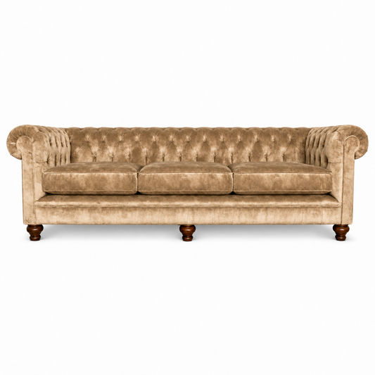 A classic Chesterfield three-seater sofa upholstered in beige velvet, featuring deep button tufting, rolled arms, and dark brown wooden legs, shown against a plain white background.