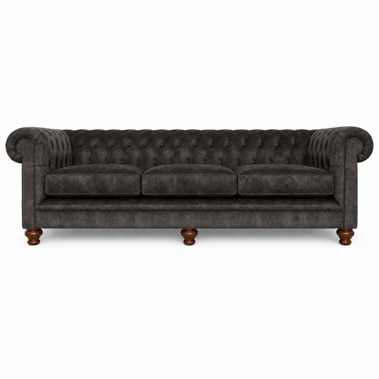 A dark gray velvet Chesterfield three-seater sofa with tufted button detailing, rolled arms, and turned wooden legs, shown against a plain white background.