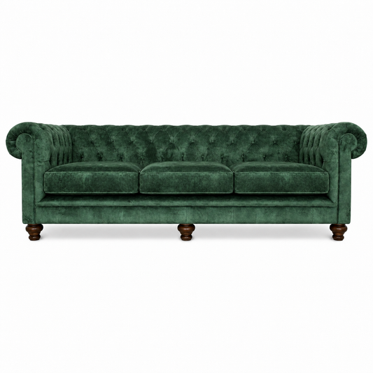 A classic Chesterfield-style sofa upholstered in deep emerald green velvet, featuring button tufting, rolled arms, three seat cushions, and dark wooden legs, shown against a plain white background.