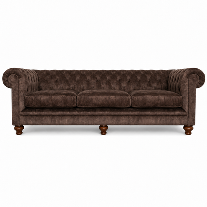 A classic Chesterfield-style three-seater sofa upholstered in dark brown velvet, featuring deep button tufting, rolled arms, and turned wooden legs, shown against a plain white background.