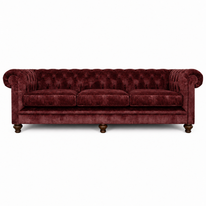 A classic Chesterfield-style three-seater sofa upholstered in deep burgundy velvet, featuring a tufted backrest, rolled arms, three loose seat cushions, and dark wooden turned legs, shown against a plain white background.