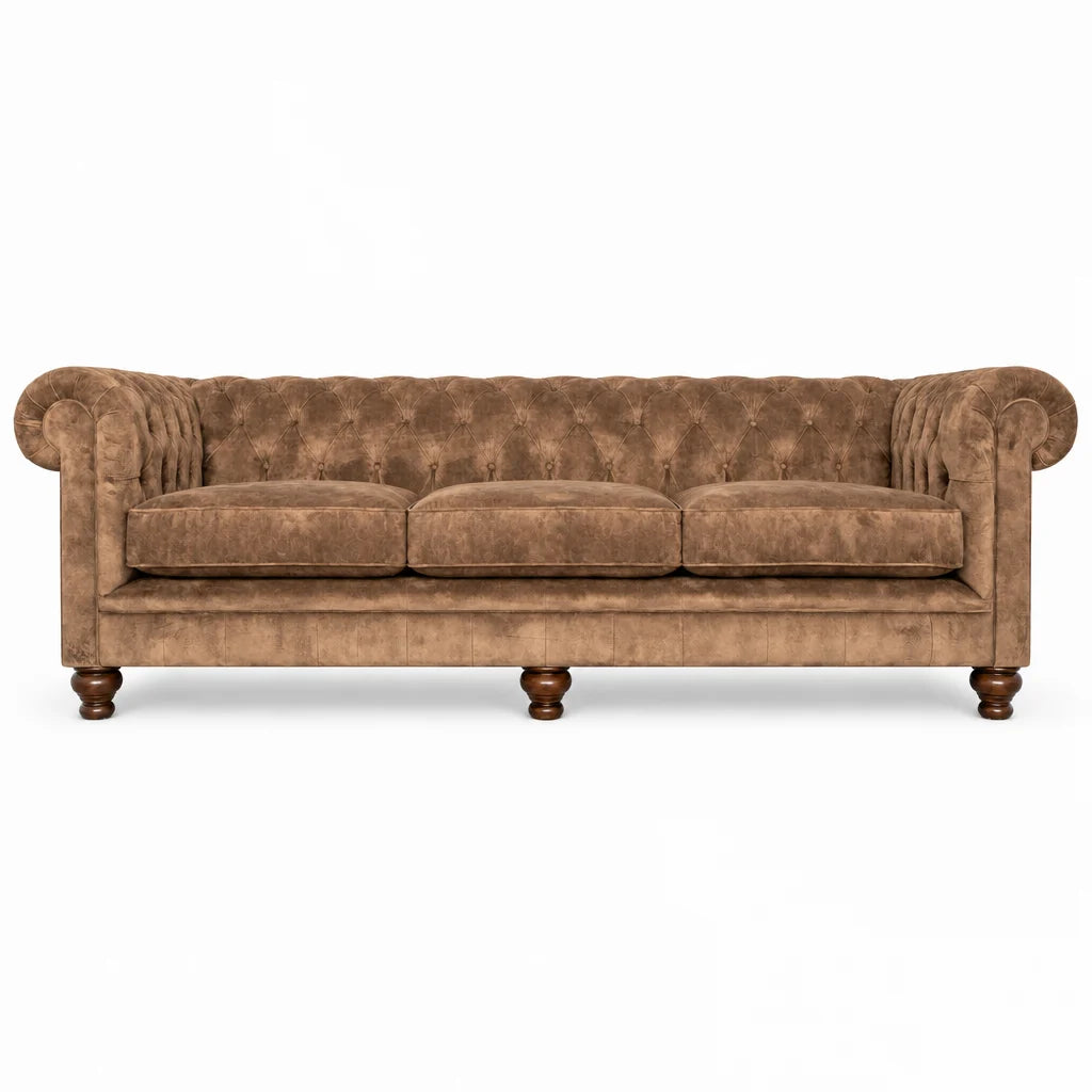 A classic Chesterfield-style sofa upholstered in brown tufted velvet, featuring rolled arms, three seat cushions, and turned wooden legs, shown against a plain white background.