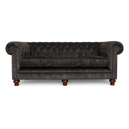 Dark gray tufted sofa with wooden legs on a white background