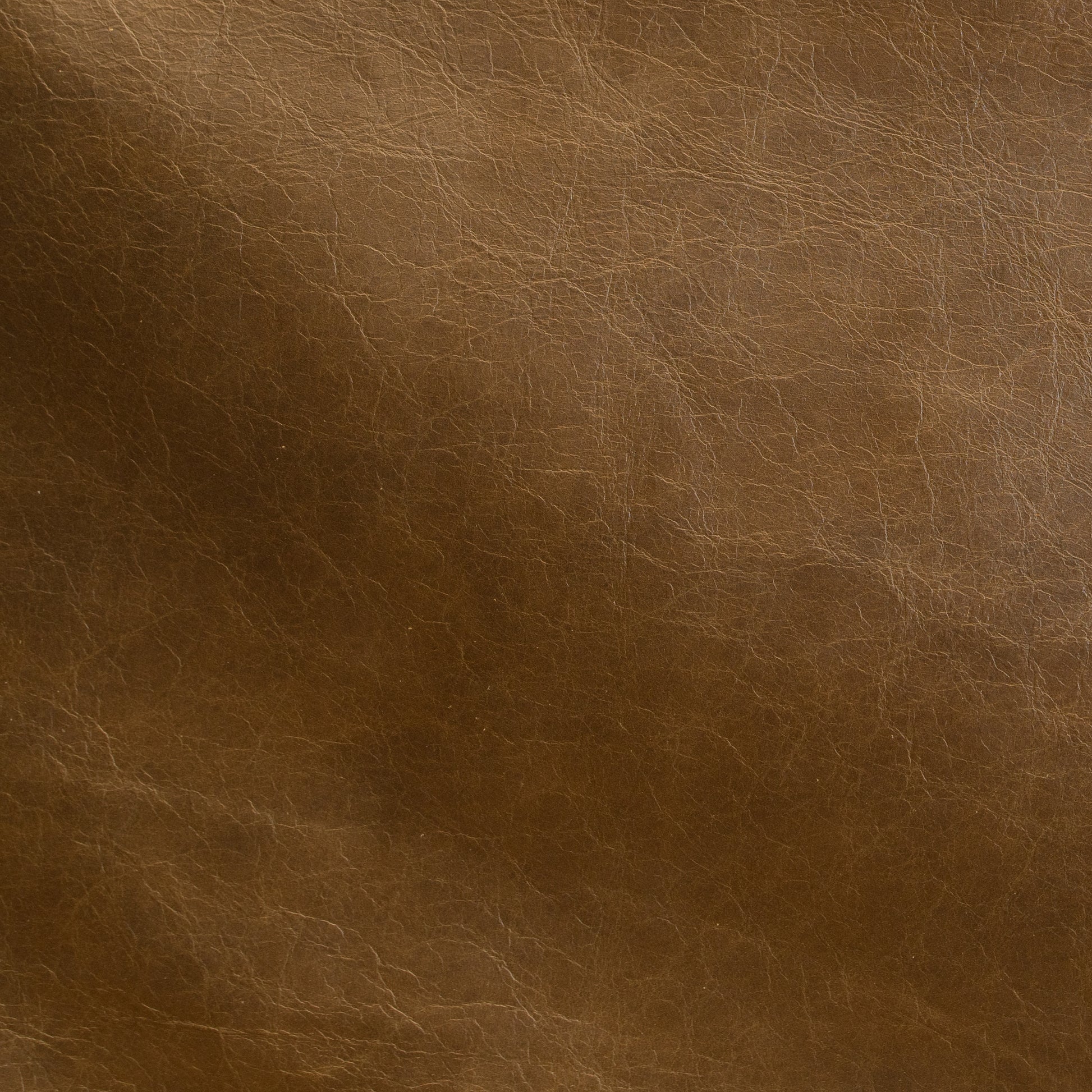 A close-up of brown leather texture with visible grain and subtle tonal variation.