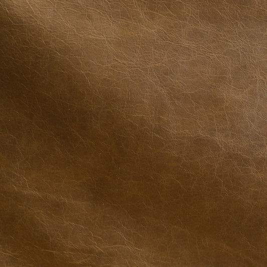 A close-up of brown leather texture with visible grain and subtle tonal variation.