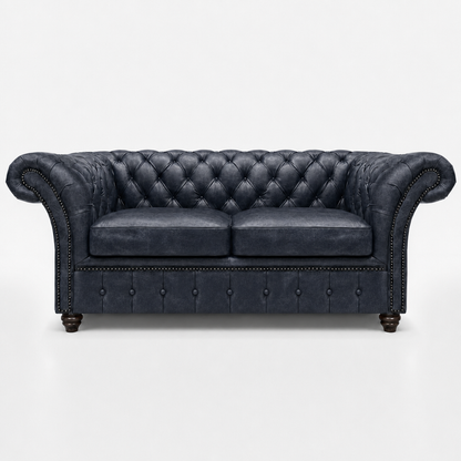 Dark gray leather sofa with tufted backrest on a white background